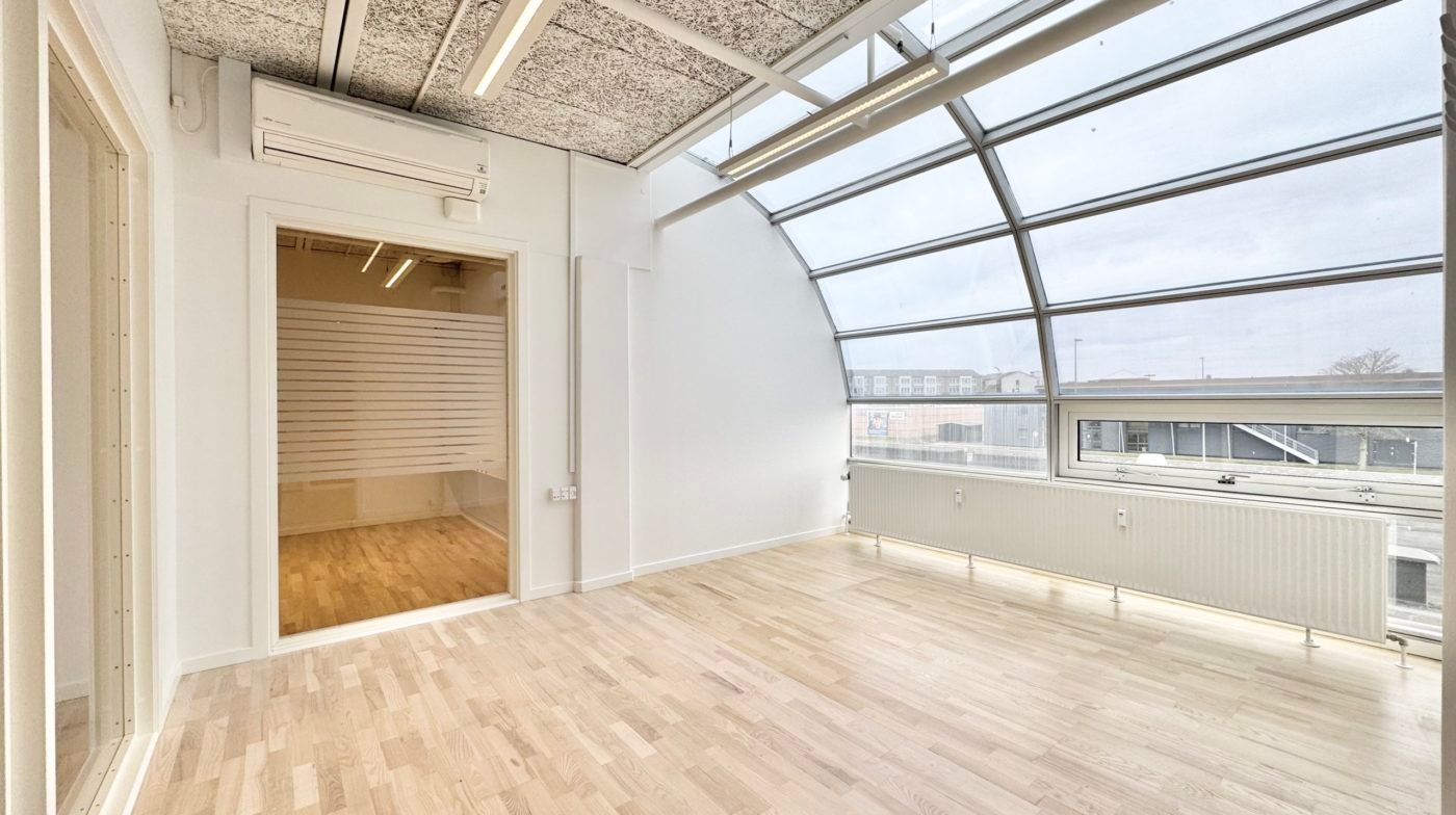 Kontorlokaler med højt til loftet og store vinduer, hvor lyse hårde trægulve er i fokus