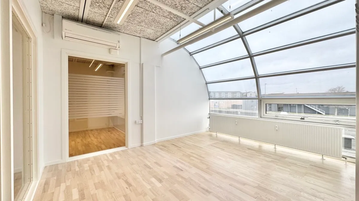 Kontorlokaler med højt til loftet og store vinduer, hvor lyse hårde trægulve er i fokus