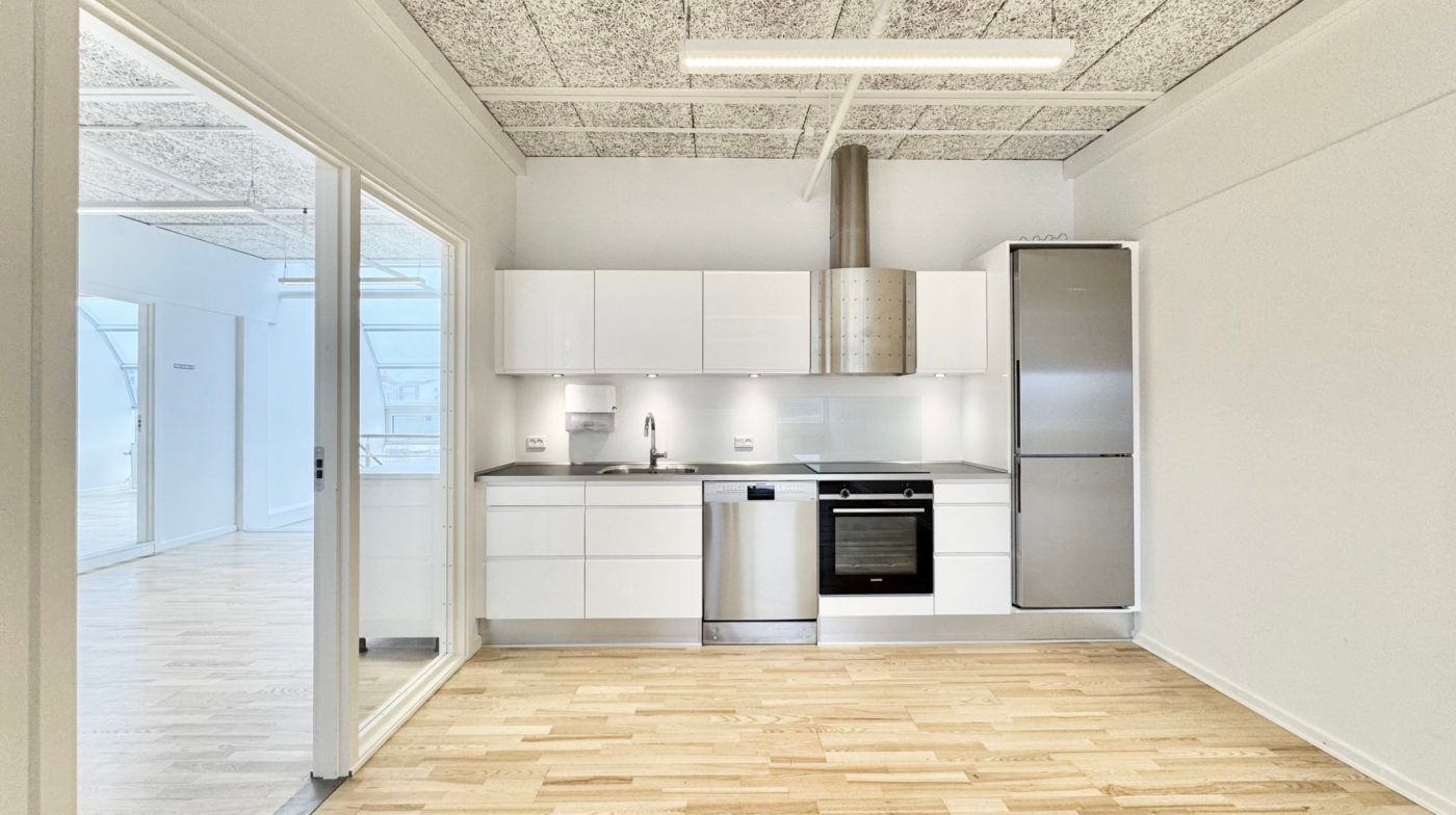 Minimalistisk køkken med hvide vægge og lysegrå loft. Moderne hvide køkkenskabe med lysegrå og hvide køkkenapparater og