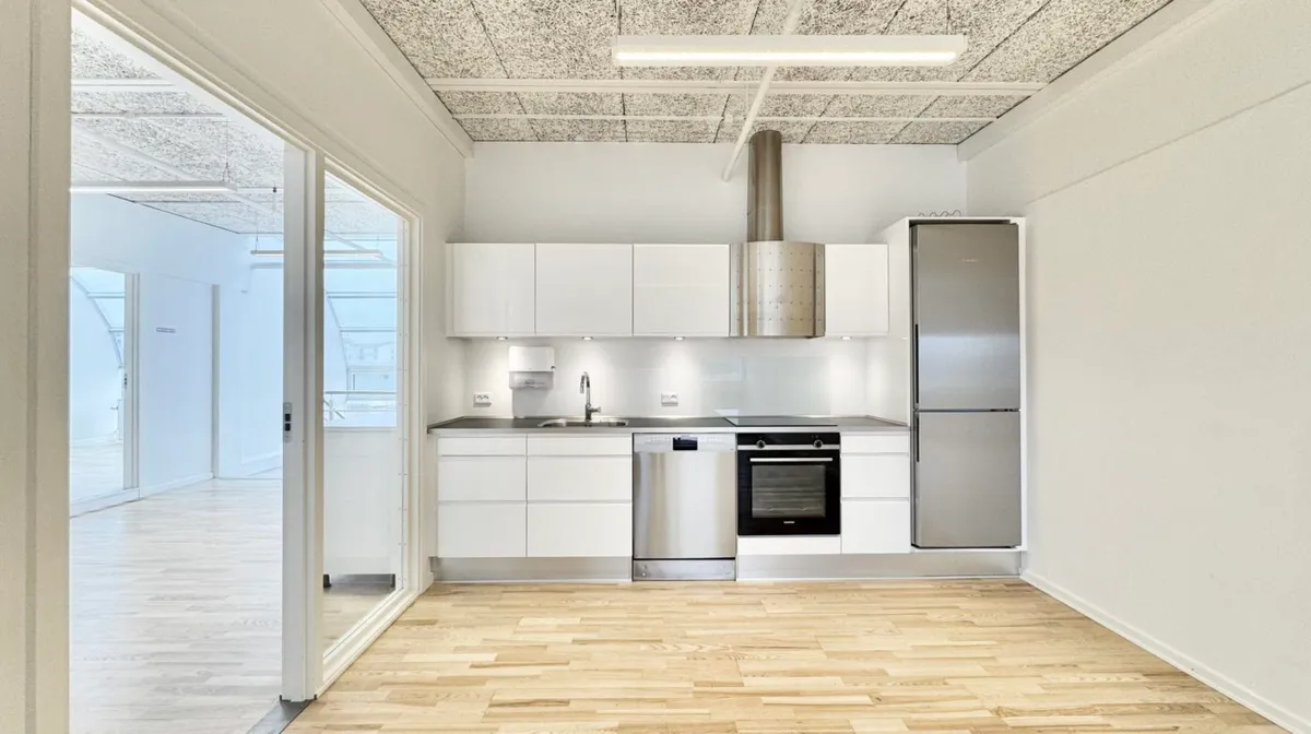 Minimalistisk køkken med hvide vægge og lysegrå loft. Moderne hvide køkkenskabe med lysegrå og hvide køkkenapparater og