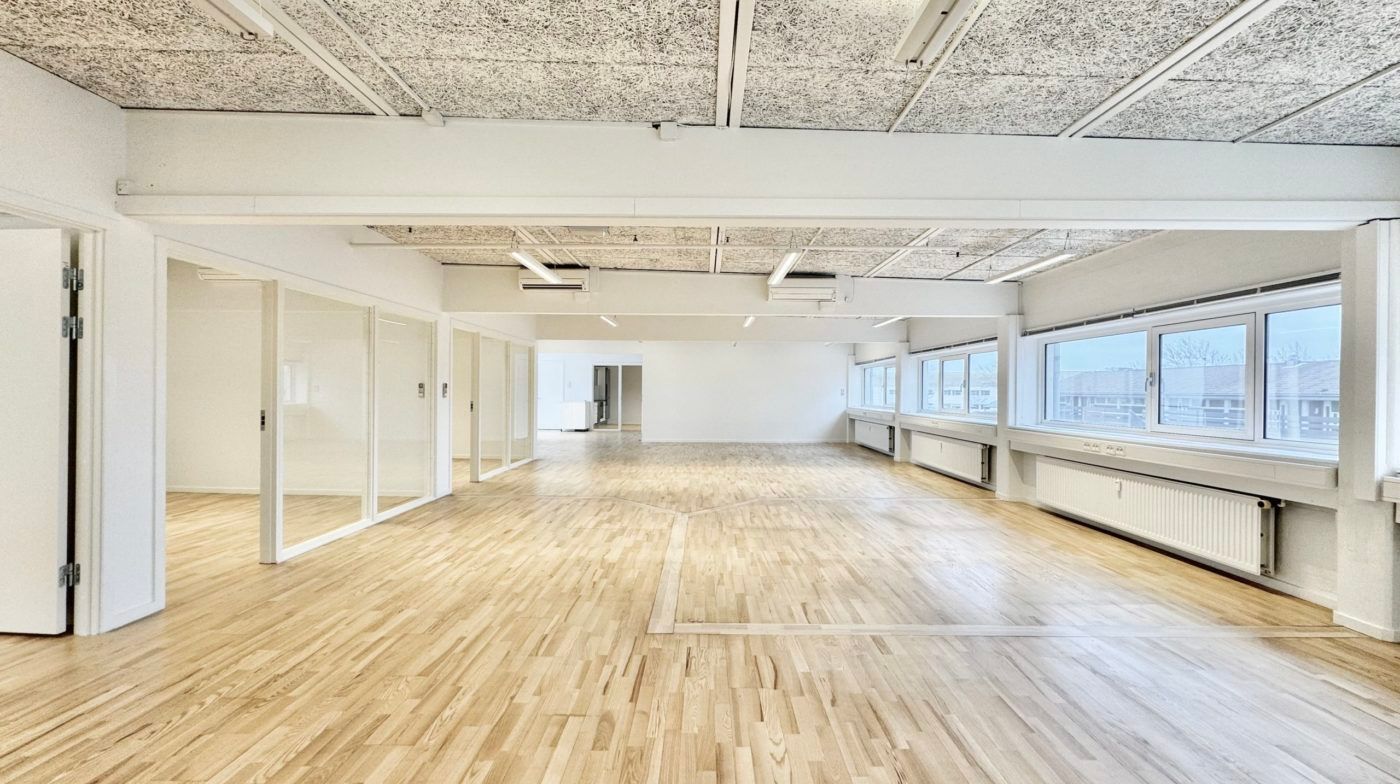 Attraktive kontorlokaler med hvide vægge og lyse trægulve, højt til loftet og store vinduer med udsigt til skoven udenfor
