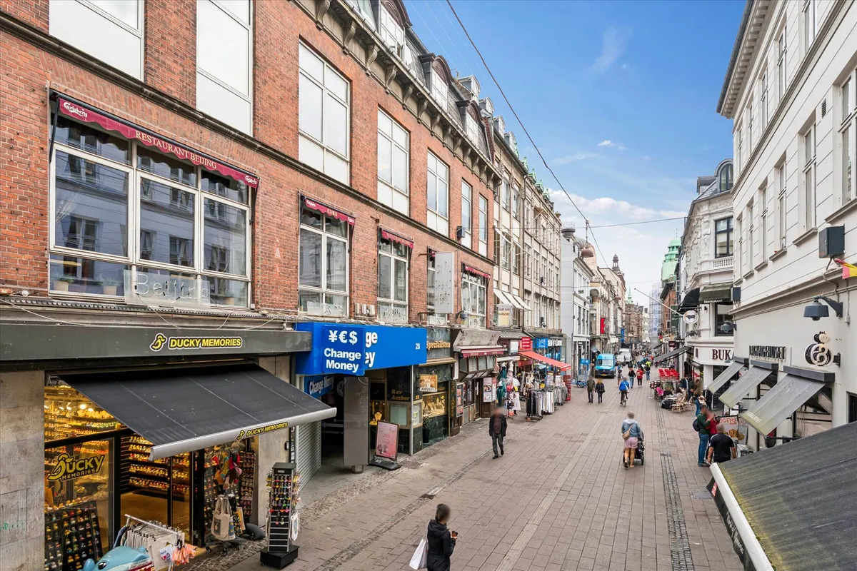 Lyst og højloftet kontor i City med udsigt over gågaden og bygningerne med forretninger og restauranter