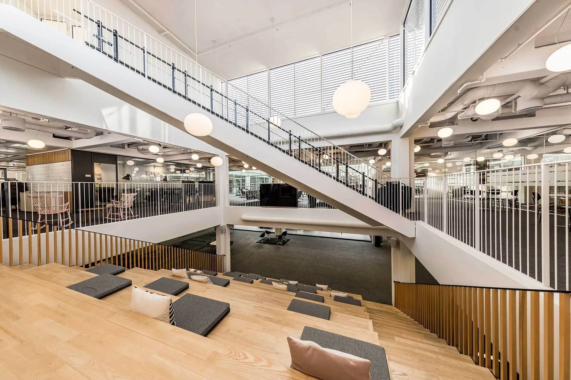 Store kontorlokaler med høje lofter, åbne områder, tre terrasser, tredje sal med trapper, lyse lamper og møbler til