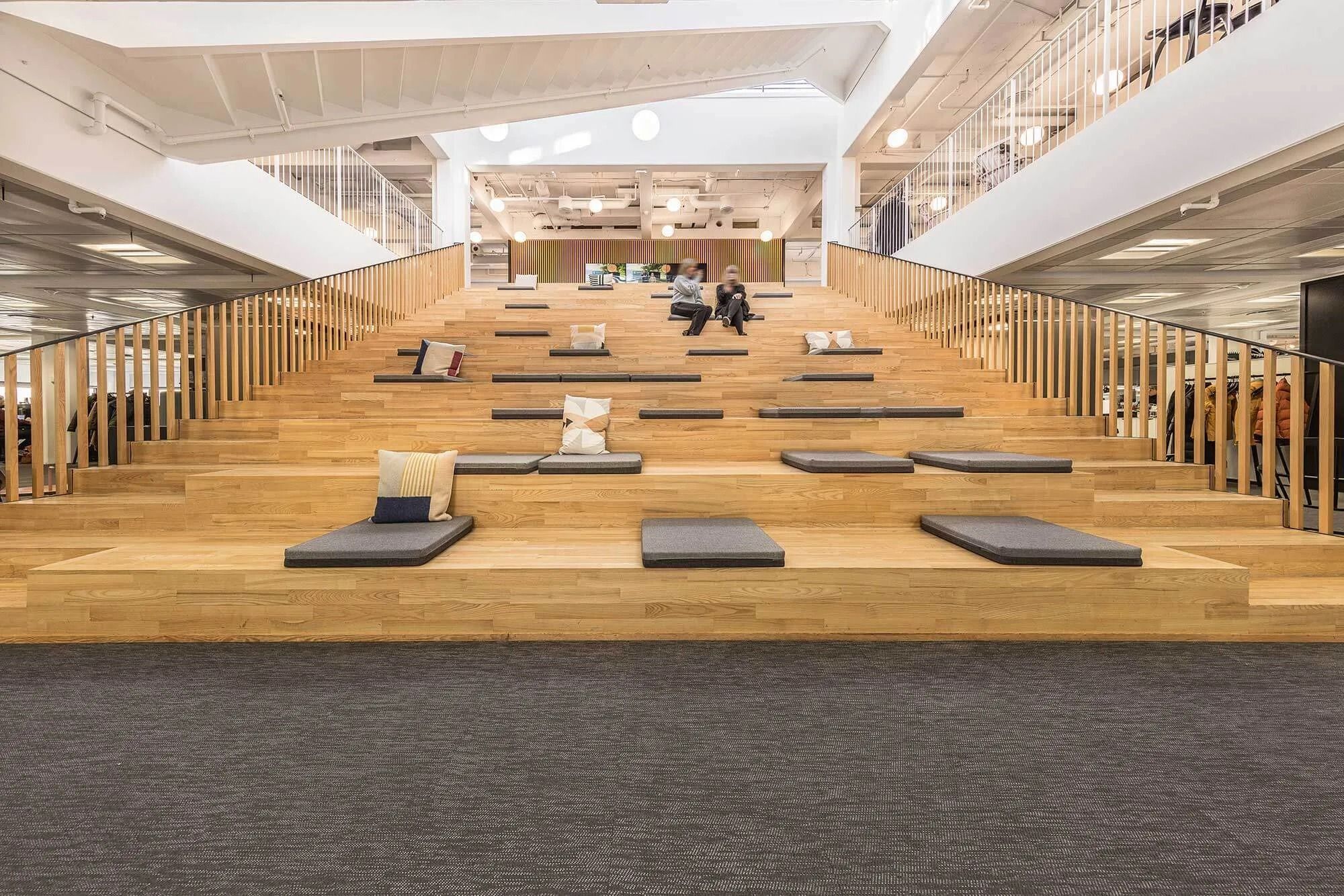 Et moderne kontor med tredje sal, hvor to personer sidder på et loft med træ og grønne pudser