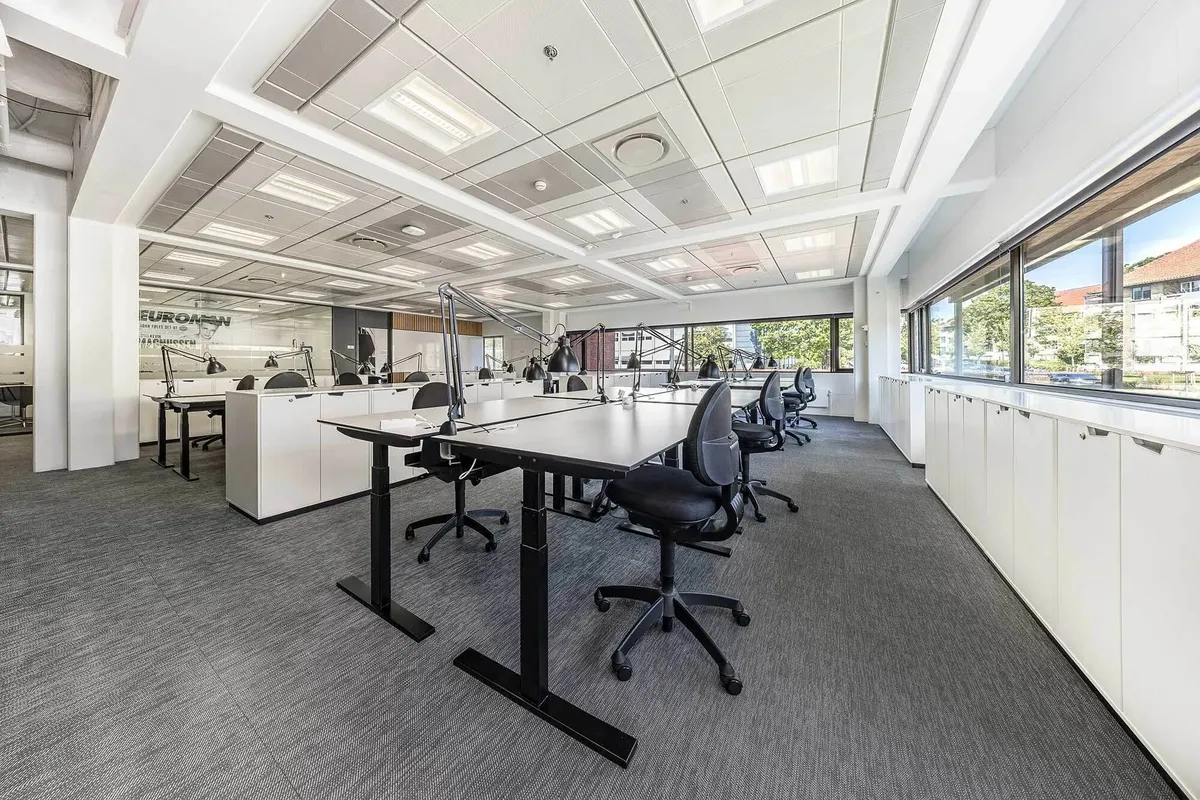 En stor og moderne kontorrum med højt gulv og møbler, vinduer og lyse lofter