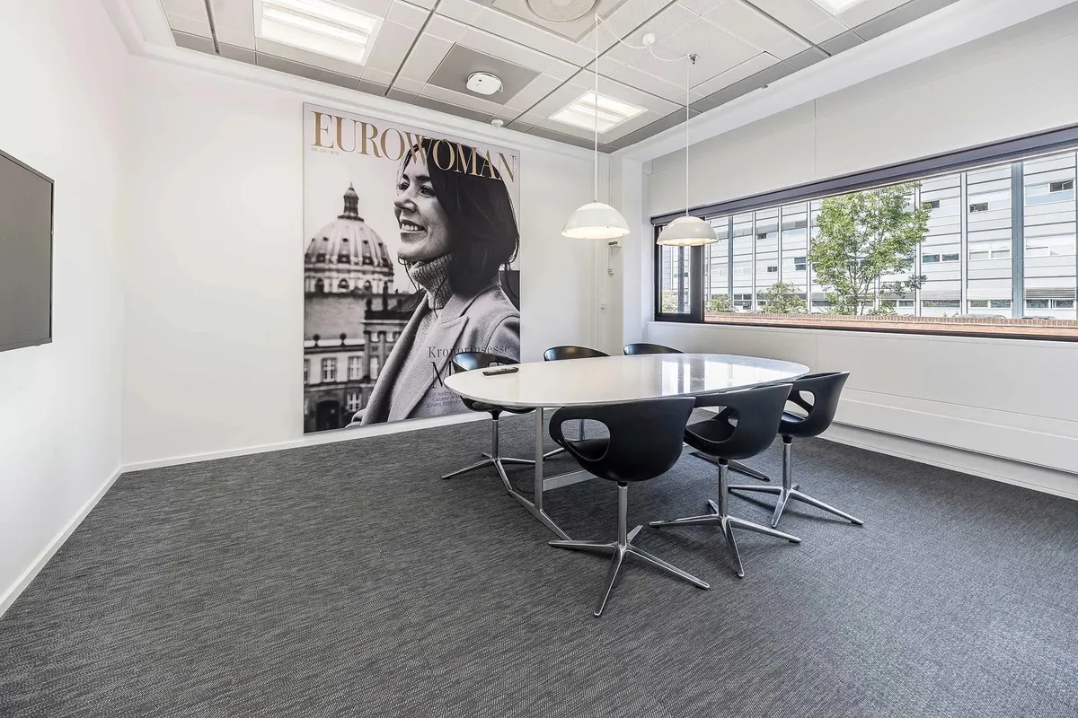 Kontorrum med møbelsæt og stor plakat med en kvinde og teksten Eurowoman
