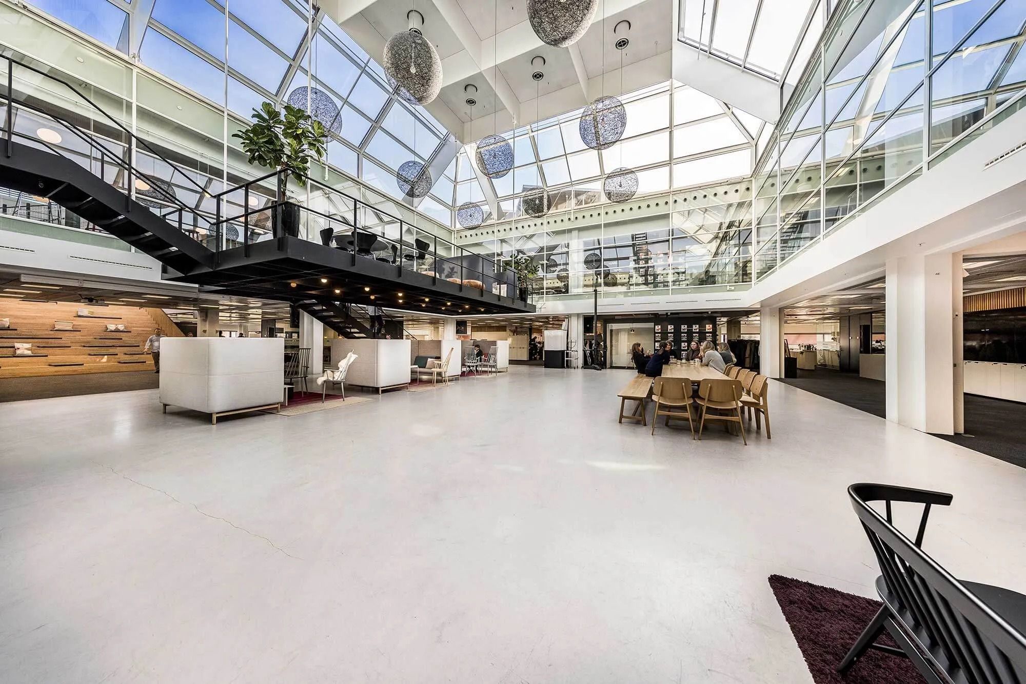 Kontor med højt loft og glasvinduer med møbler og plante i en moderne interiørdesign