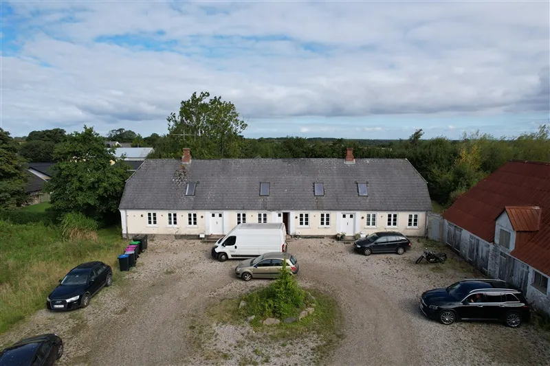 Investeringsejendom med parkeringsplads og flere biler parkeret, hvor en hvid varevogn er parkeret lige foran