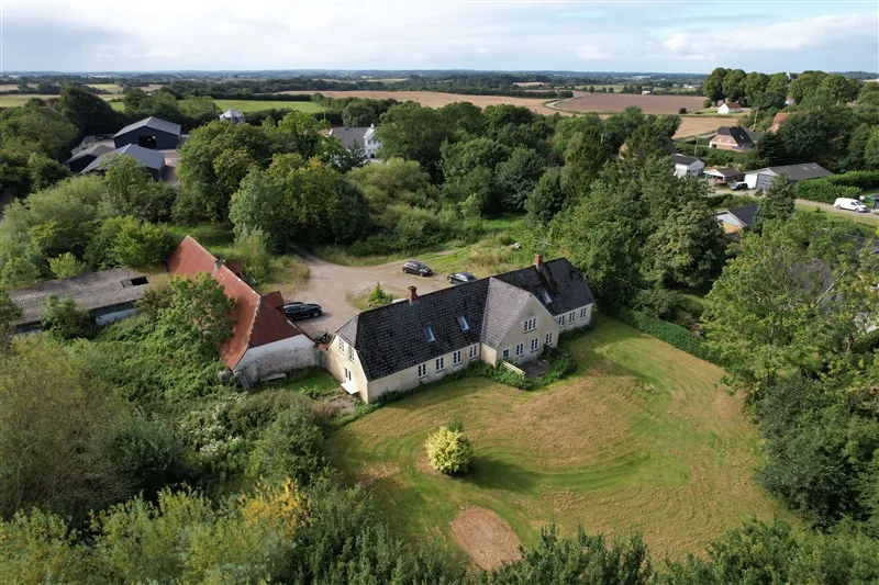 Huse og biler på en ejendom med græsplæne og træer i landsbyen Moltrup i Danmark