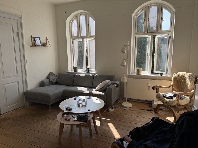 Foto af et moderne interiør med to vinduer, en høj hvid lampe og trægulve