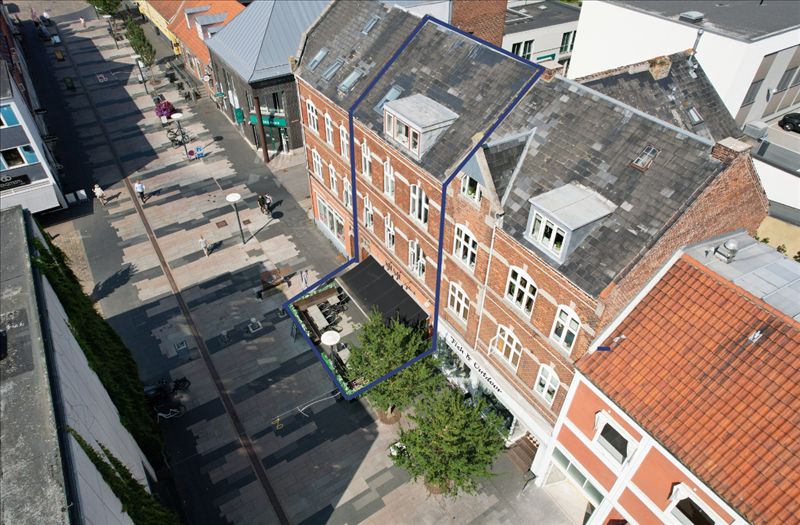 Københavner gadestrøg med butikker og gågade på Jyllandsgade, forretningslokaler med terrasse og grønne planter og en stor