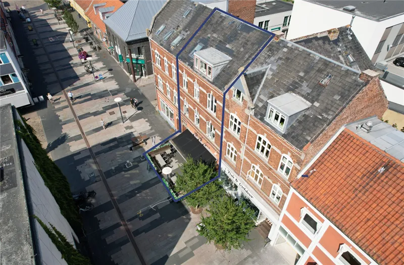 Københavner gadestrøg med butikker og gågade på Jyllandsgade, forretningslokaler med terrasse og grønne planter og en stor