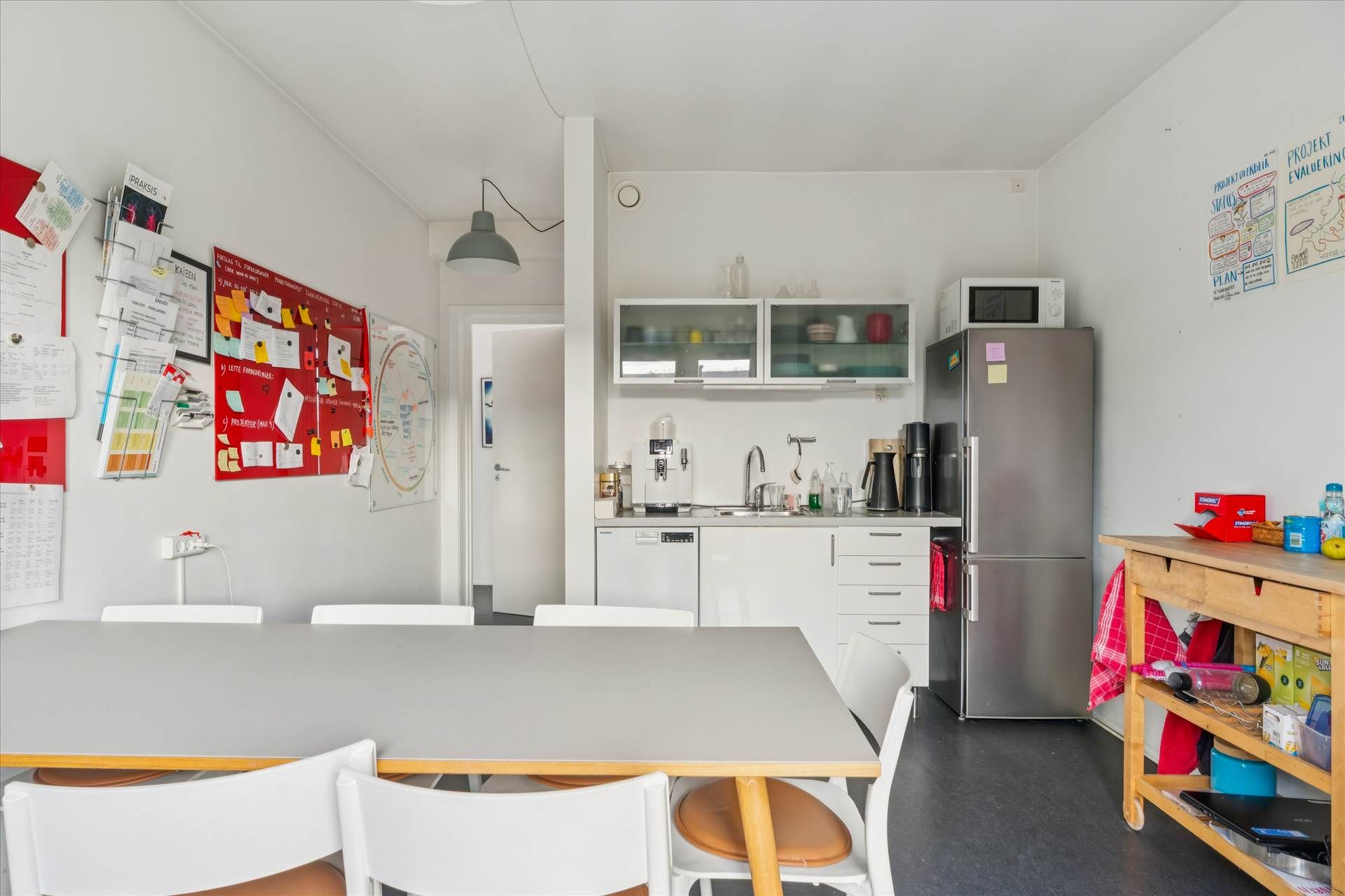 På dette foto ses et moderne køkken med et højloft, lyse og rene vægge og møbler i hvidt og brun læder