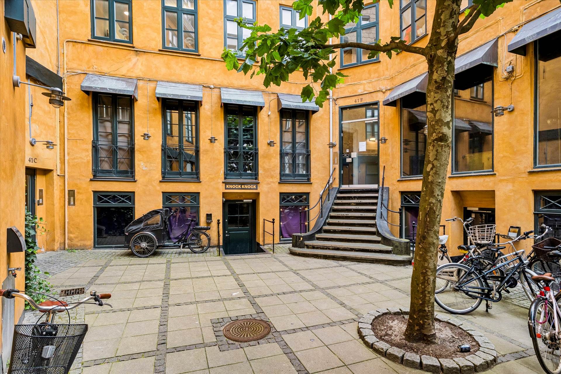 Strøget i København, med gul malet bygning og møbeludsalg i første sal, med adgangsdør og trappe op til anden sal