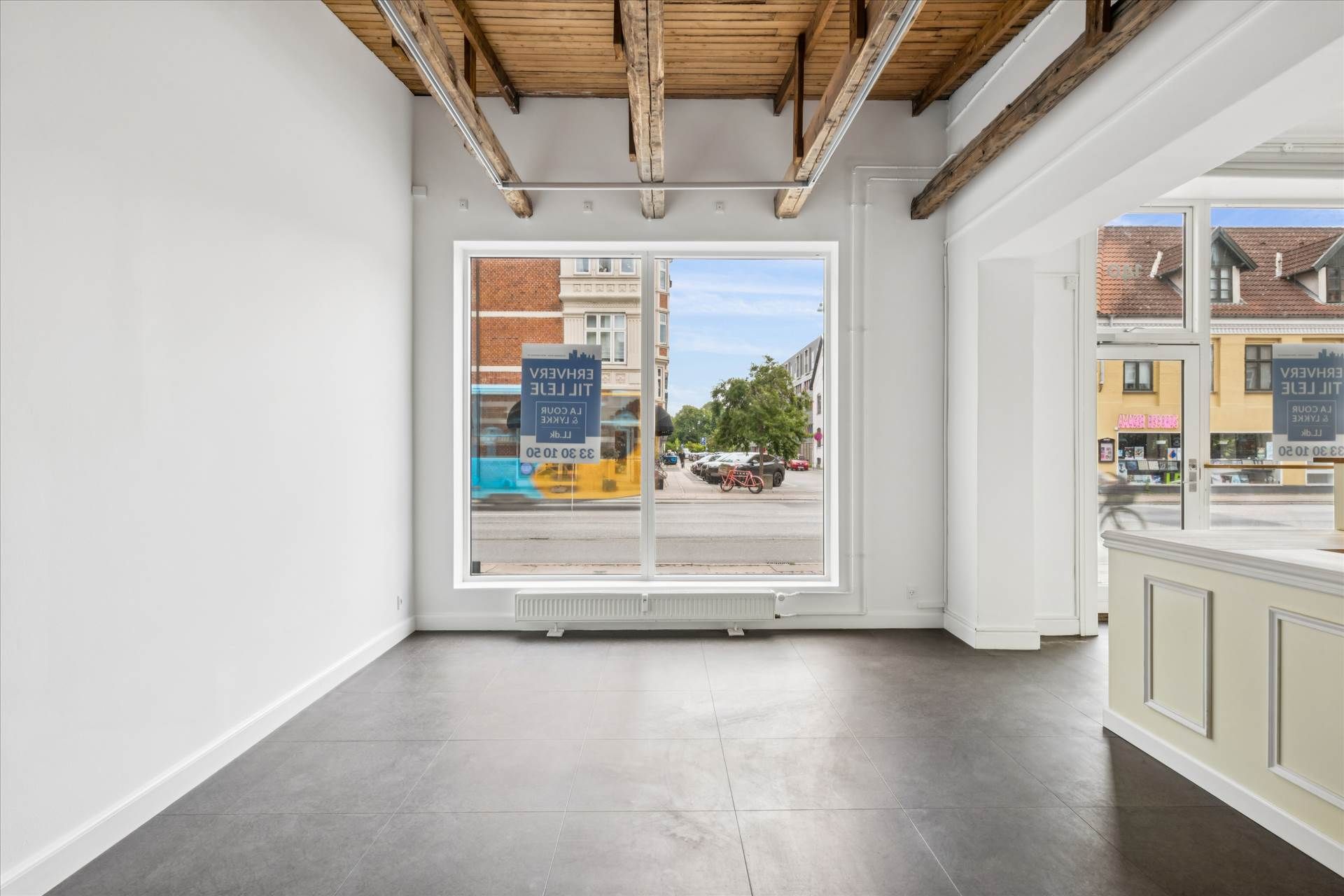 Butik i København med store vinduer, hvor der er reklameskilt med teksten "FOR RENT" og et skriftstykke med "FOR SALE" og