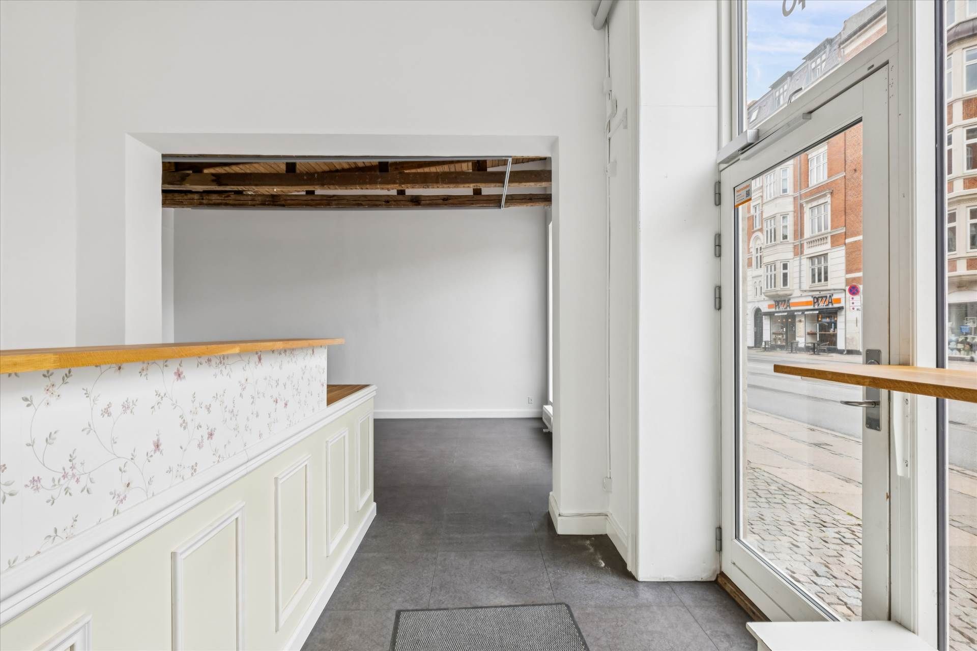 Moderne butik med hvide vægge og loft, trægulv og glasdør med træbånd på Amagerbrogade. På krydset af Englandsvej og