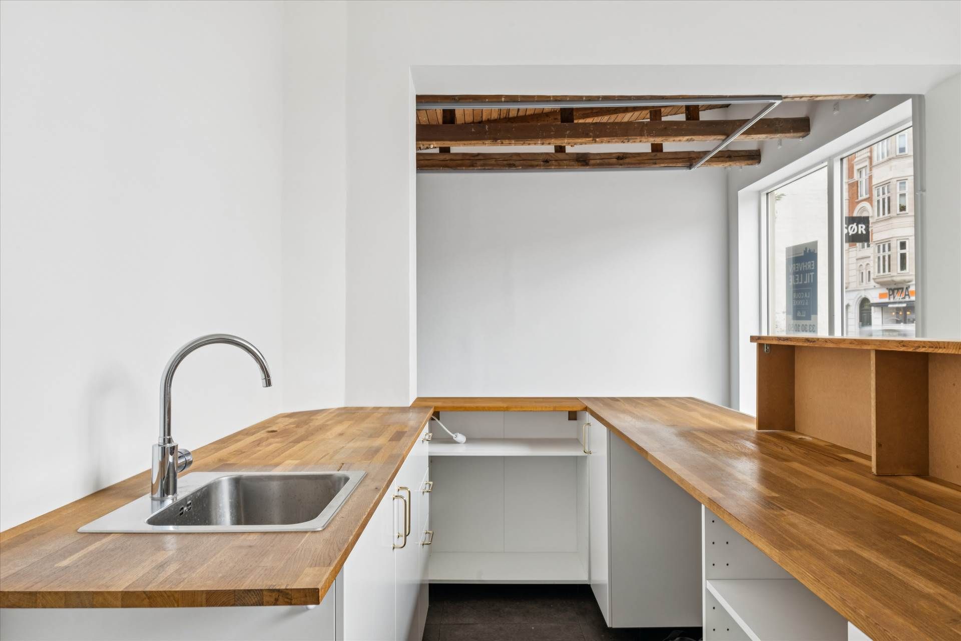 Foto af en moderne køkkendesign med højloft og trægulve samt lyse, smukke hjørner. Højloftet er dekoreret med lyse, smukke