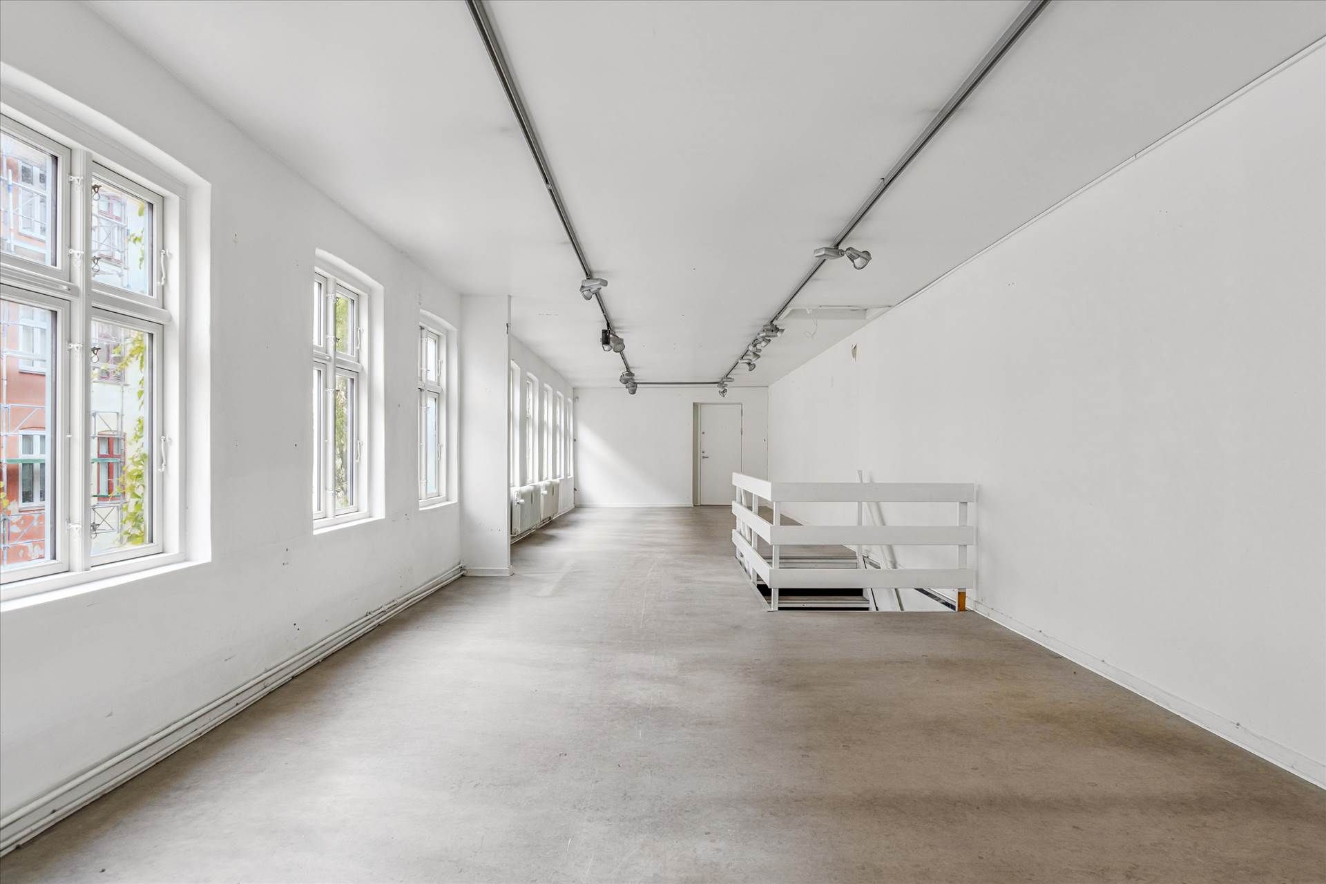 Hall med hvide vægge, højt til loftet, vinduer, trapper og moderne gulvbelægning og lysekroner