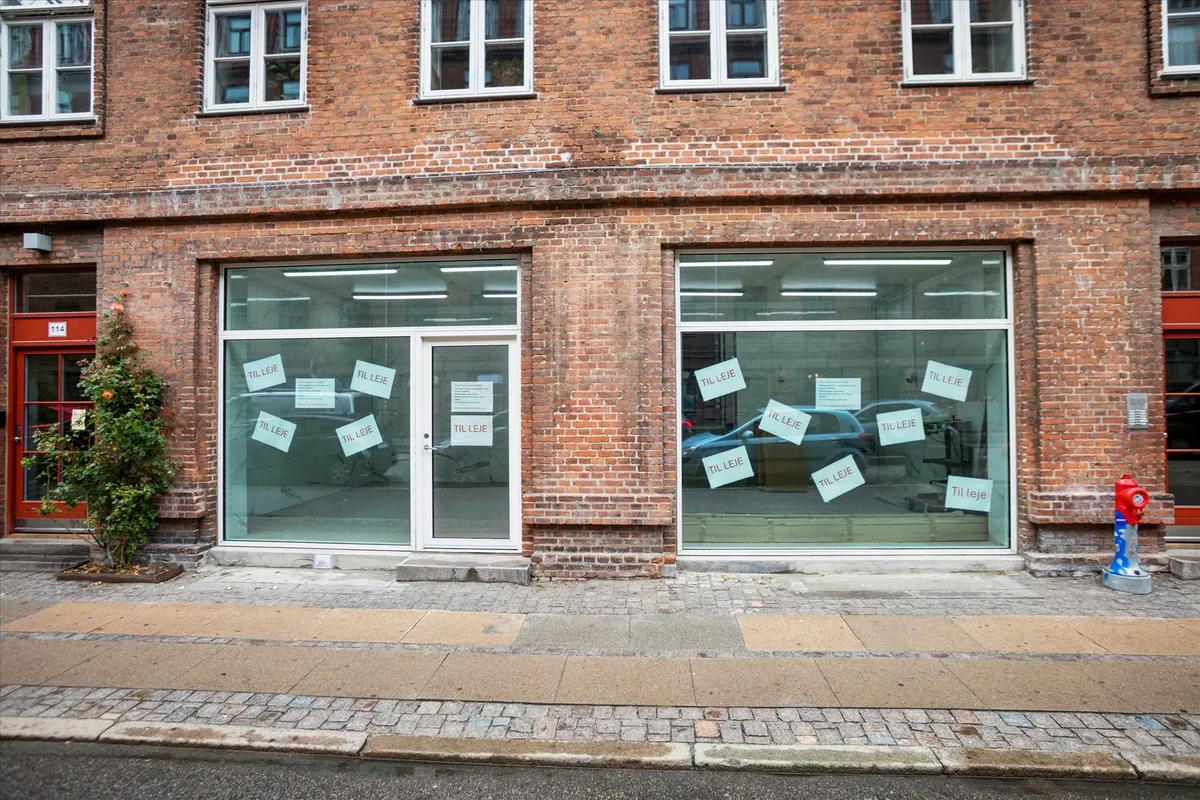 Københavnsgade med røde brandvandsslanger og en fredelig facade med røde vinduer og hvide indramninger og et skrift på