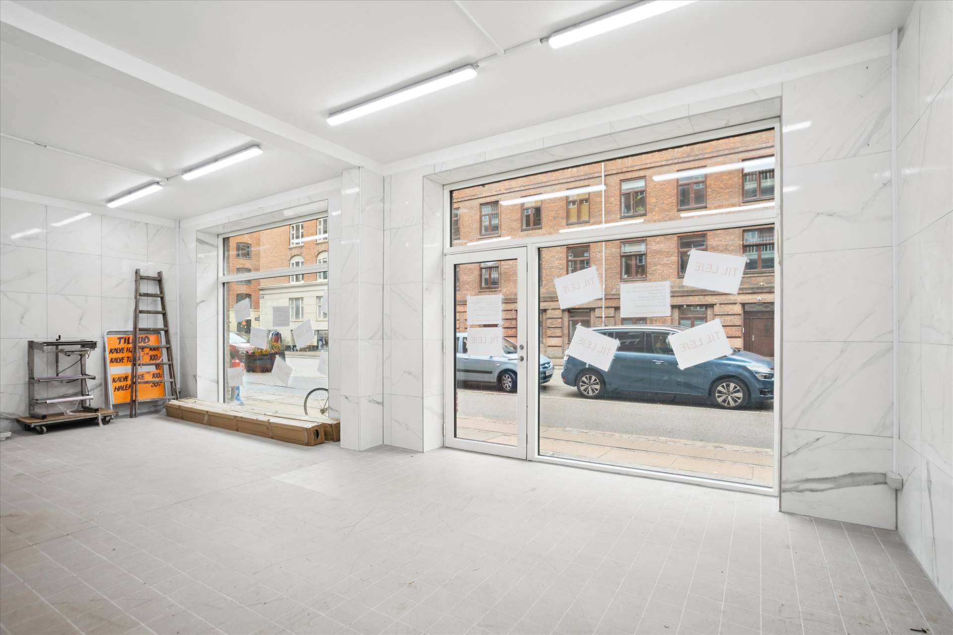 Erhvervslokaler i bymidten med store vinduer og hvide marmorvægge, fuldt udstyret til detailhandel og service med moderne