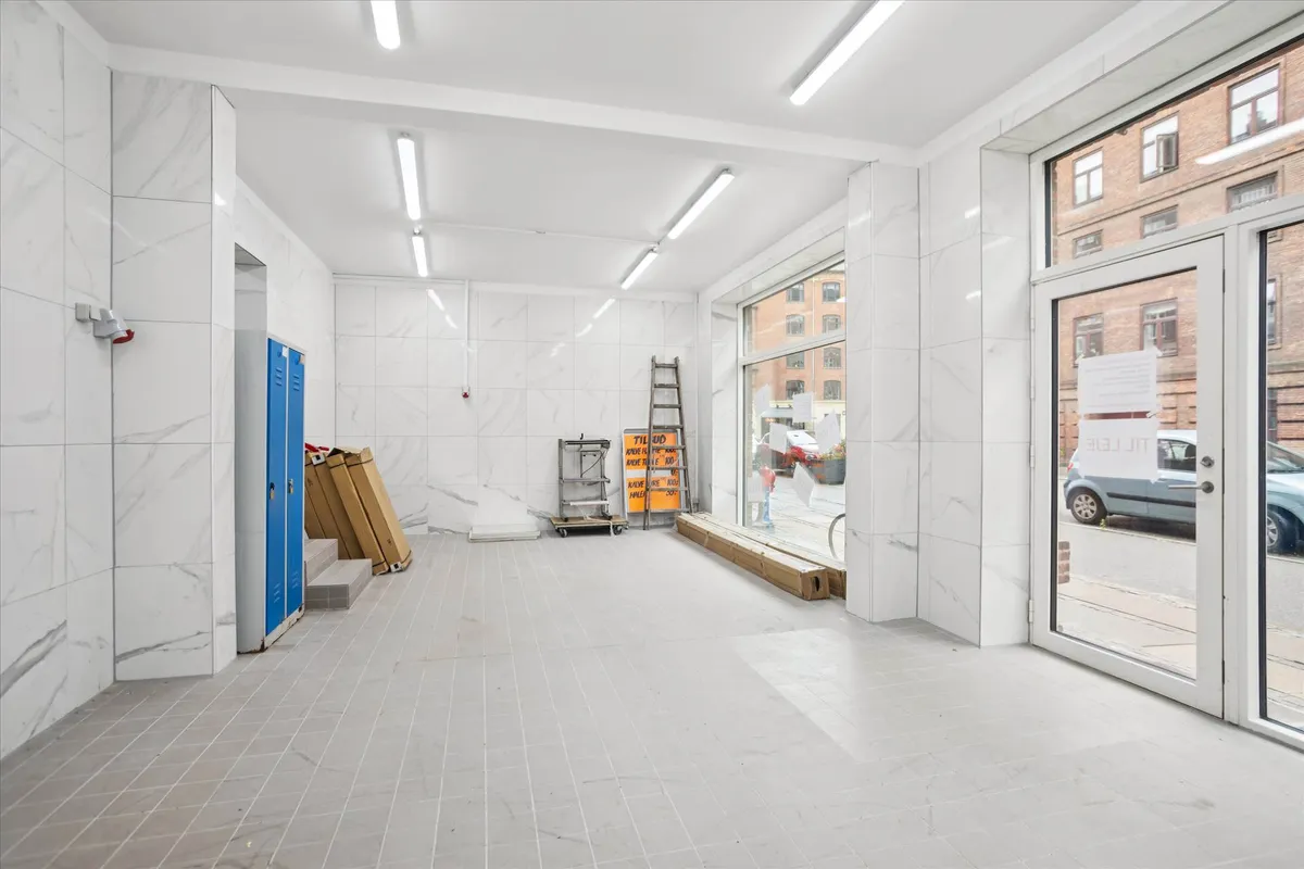 Lokaler med marmorbeklædning og hvide lofter til udlejning med vinduer og døre mod gade med biler og bygninger