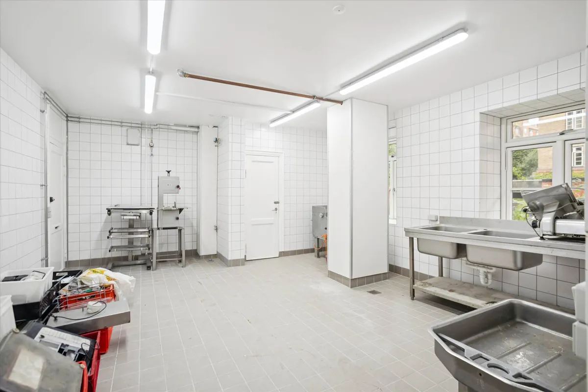 Erhvervslejemål med køkken, lager og toilet i et erhvervsområde med smukke synlige vinduer og lyse loftslampe.