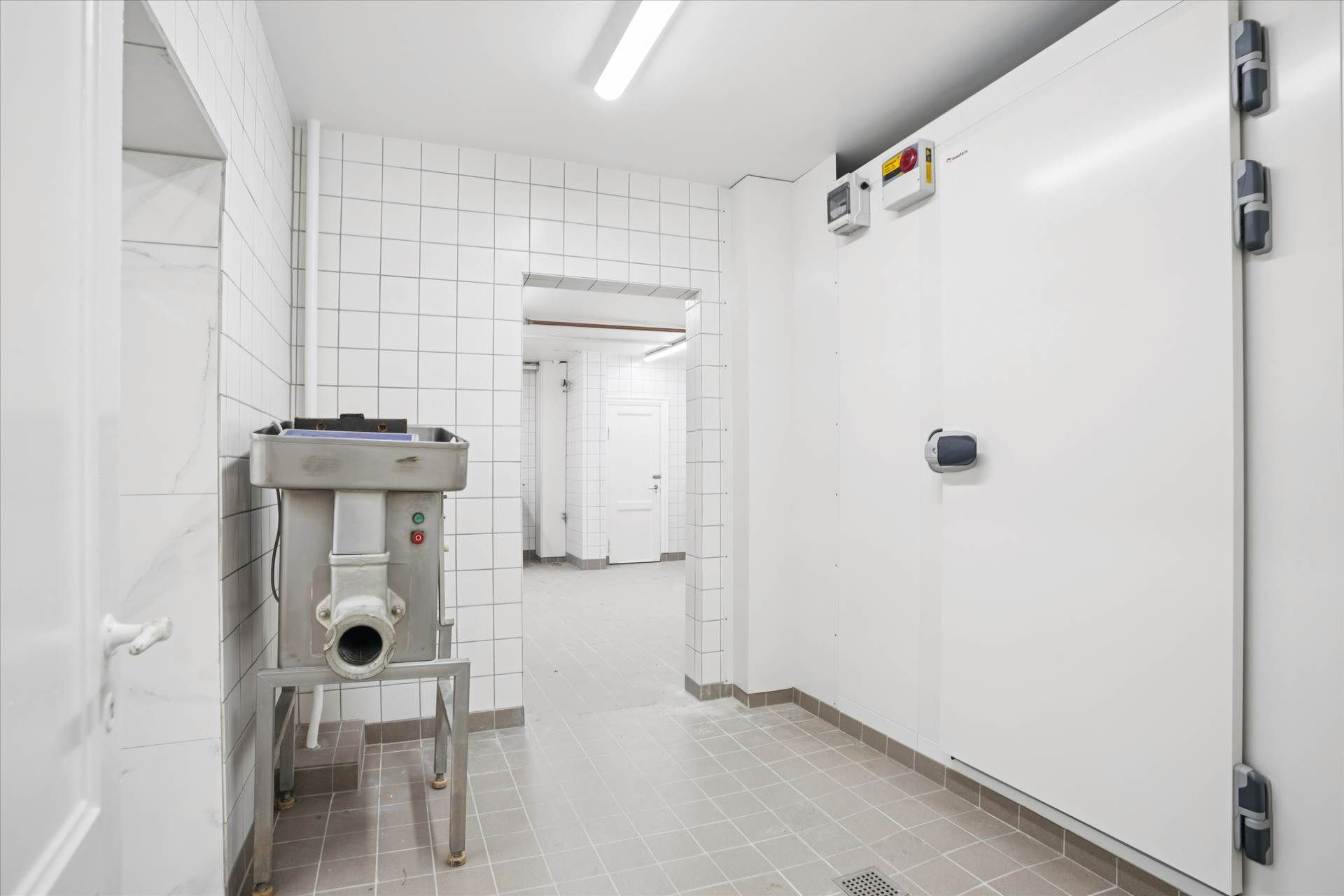 En ren og velorganiseret kølelager med metalliske vægbeklædning og en stor, hvid køleskab med et digitalt display til