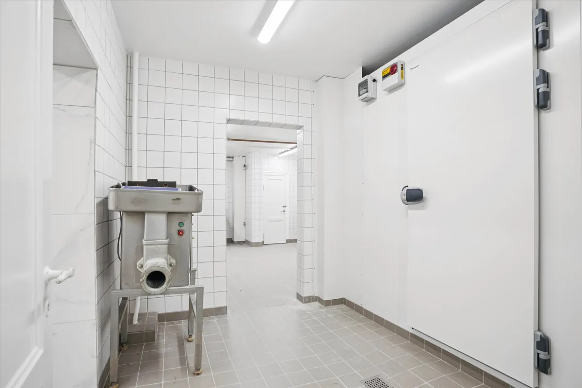 En ren og velorganiseret kølelager med metalliske vægbeklædning og en stor, hvid køleskab med et digitalt display til