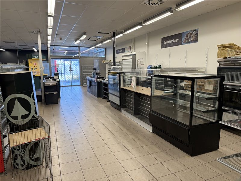 En stor butik med stolpe, kasseapparat, udstillingsskabe og lysekroner, der er tændt på loftet