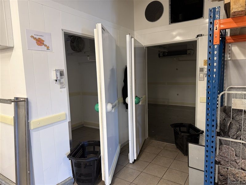 Sorte kurve med grønne balloner står i en kølingslager og ventiler og et skilt er ophængt på væggen