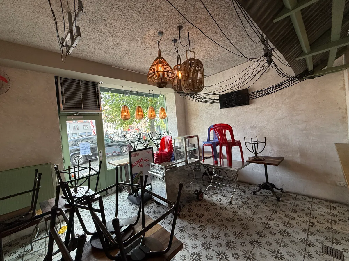 Inde i café med tomme stole og stole stablet i hjørner og udstillingsborde med lysekroner, stole og træborde