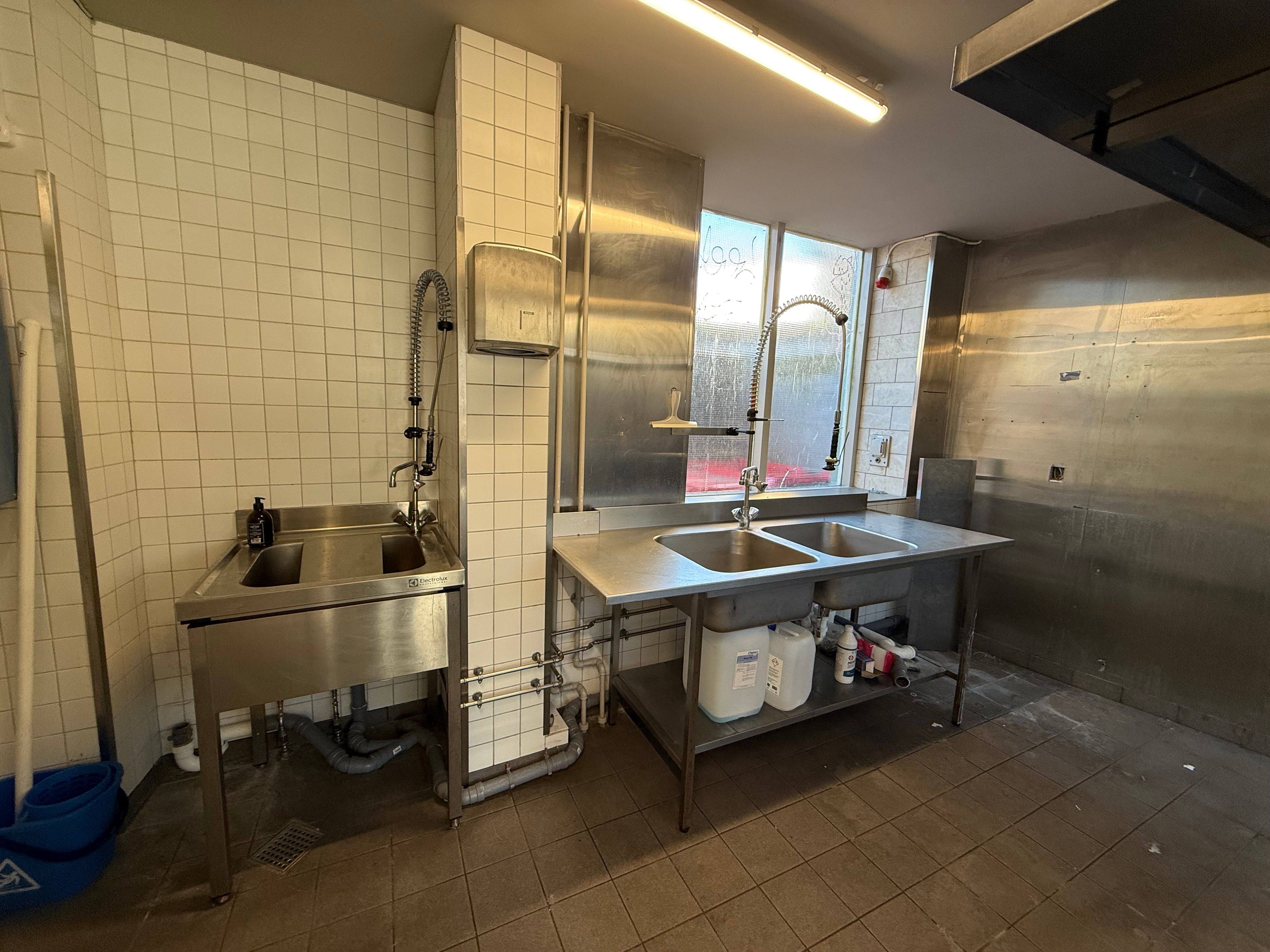 Rent og veludstyret køkken med 2 vaskebakker, 2 vandhaner, 2 stålborde og 2 bøtter til affald på Nørrebrogade 153 i København