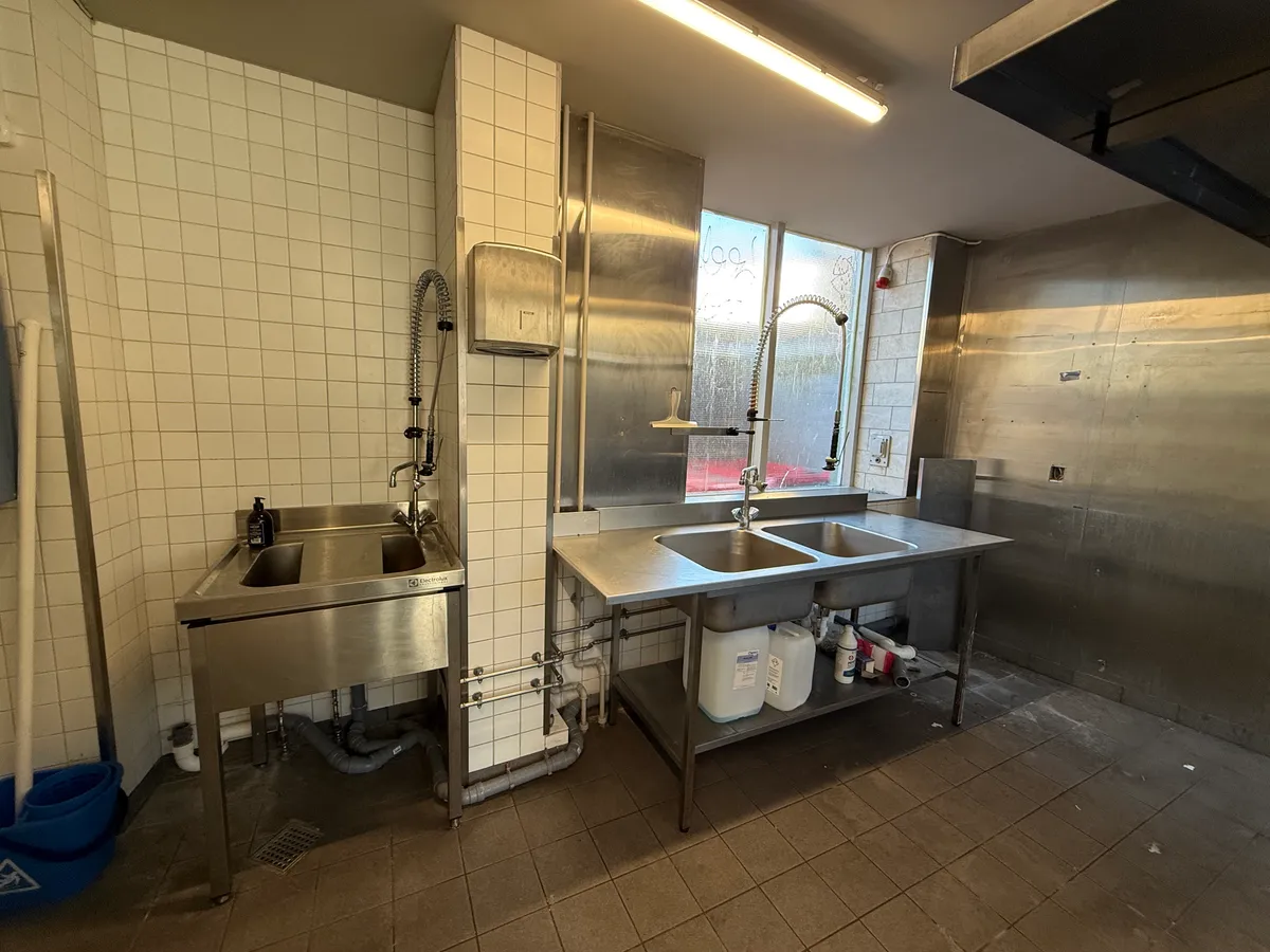 Rent og veludstyret køkken med 2 vaskebakker, 2 vandhaner, 2 stålborde og 2 bøtter til affald på Nørrebrogade 153 i København