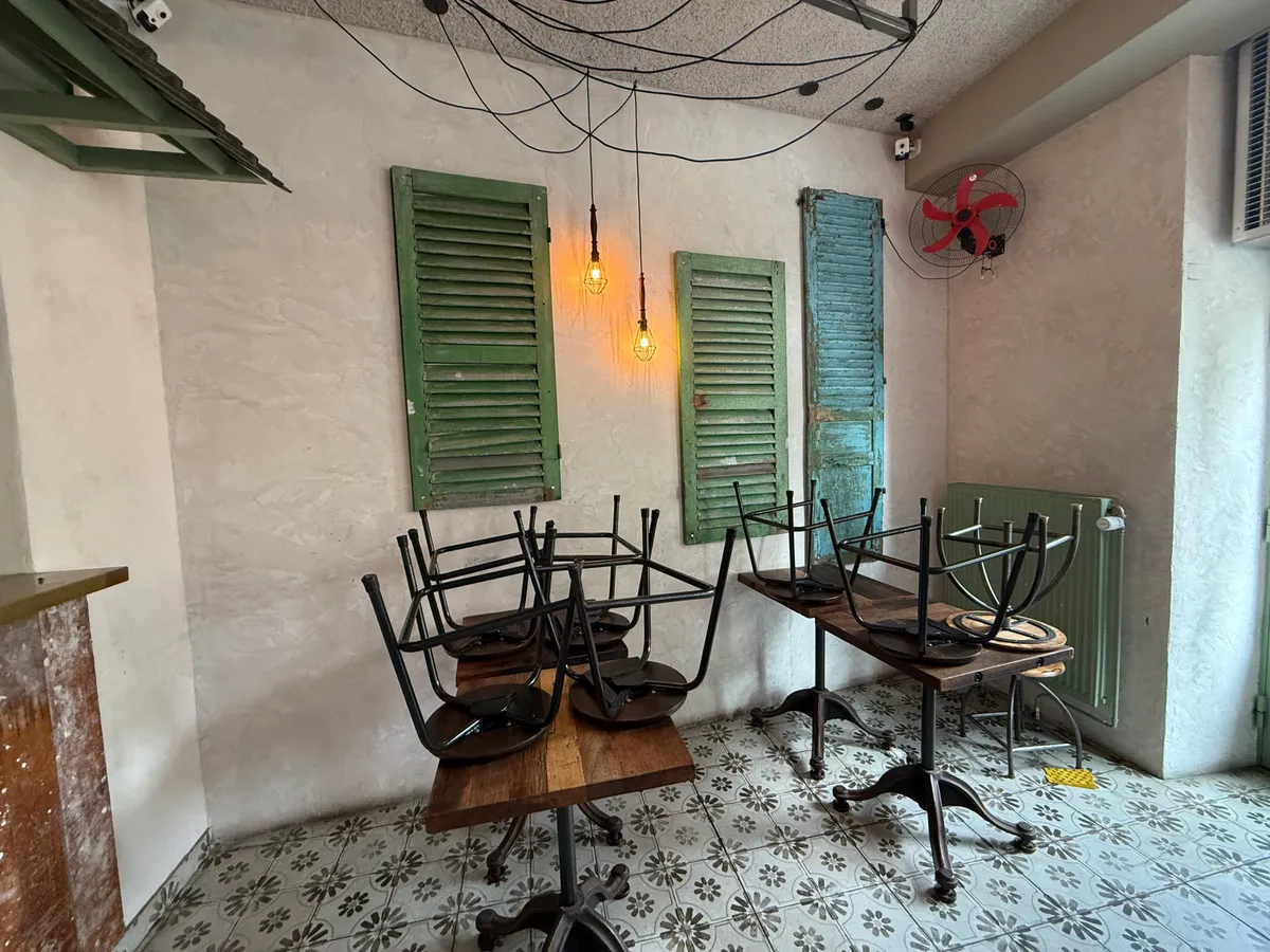 En tom restaurant med fire stole og to stolpeborde samt en ventilator og et radiator.