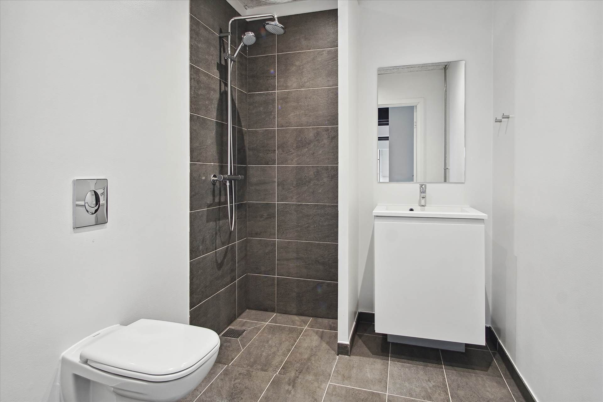 Hvidt badeværelse med torvejskabler, hvid toilet, hvid spejl, hvid vask og hvidt loft