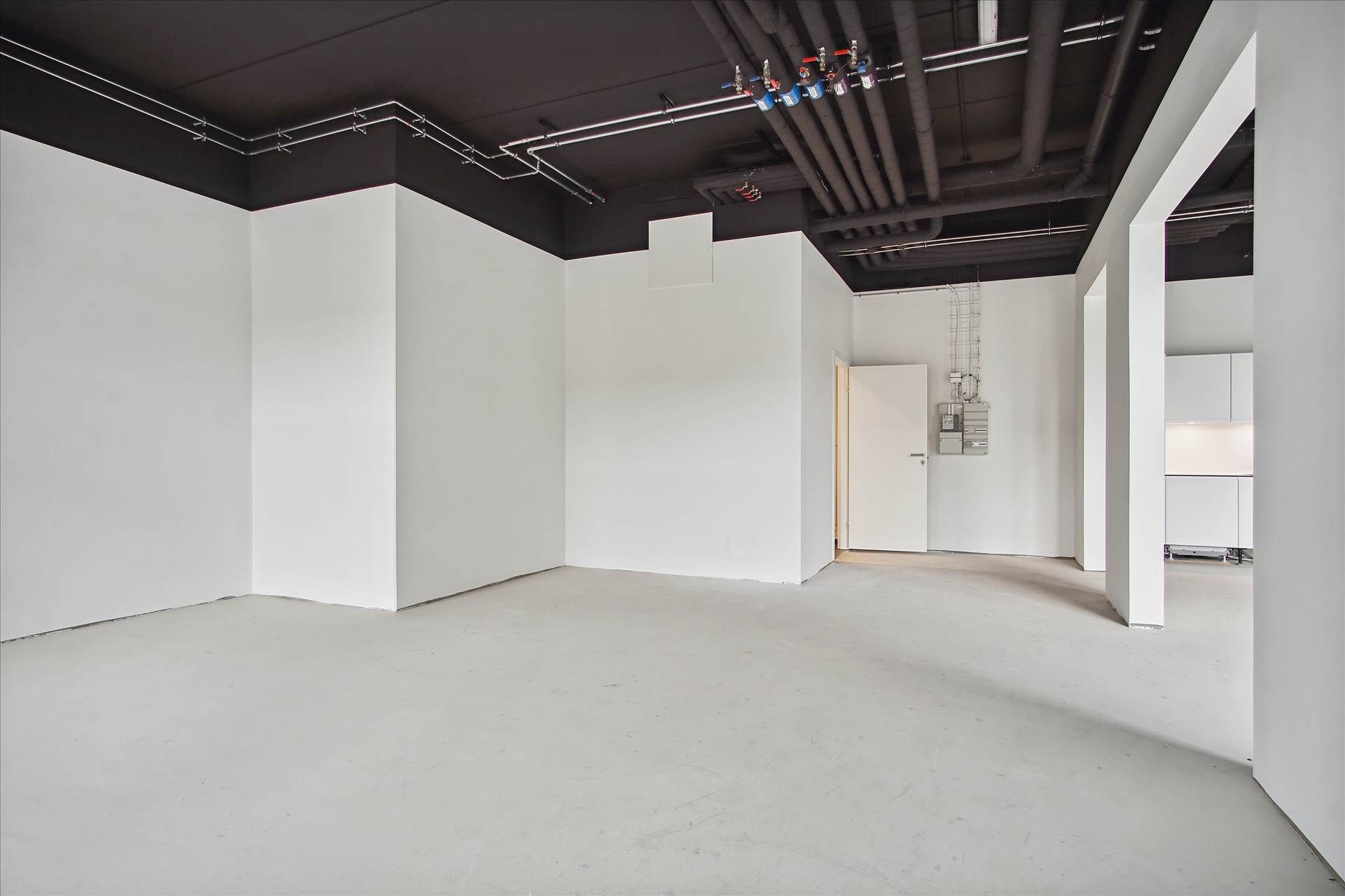 Et tomt rum med hvide vægge og gulv samt et hvidt loft med svage skygger og sorte accenter