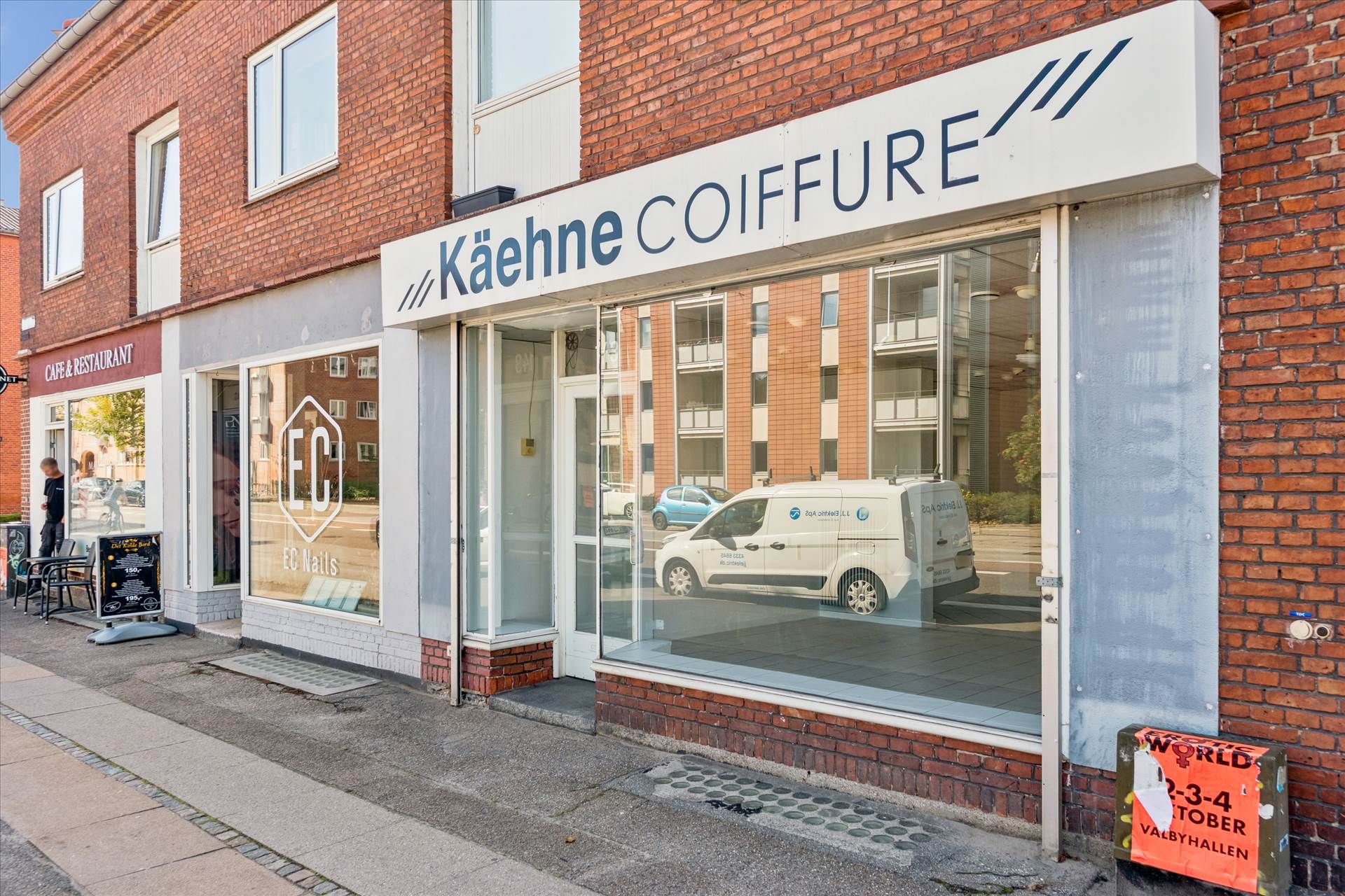 Kæhne Coiffure frisørsalon med et glasvindu og et hvidt skilt med blå tekst på Ålekistevej, et kundeparkeringsområde og en