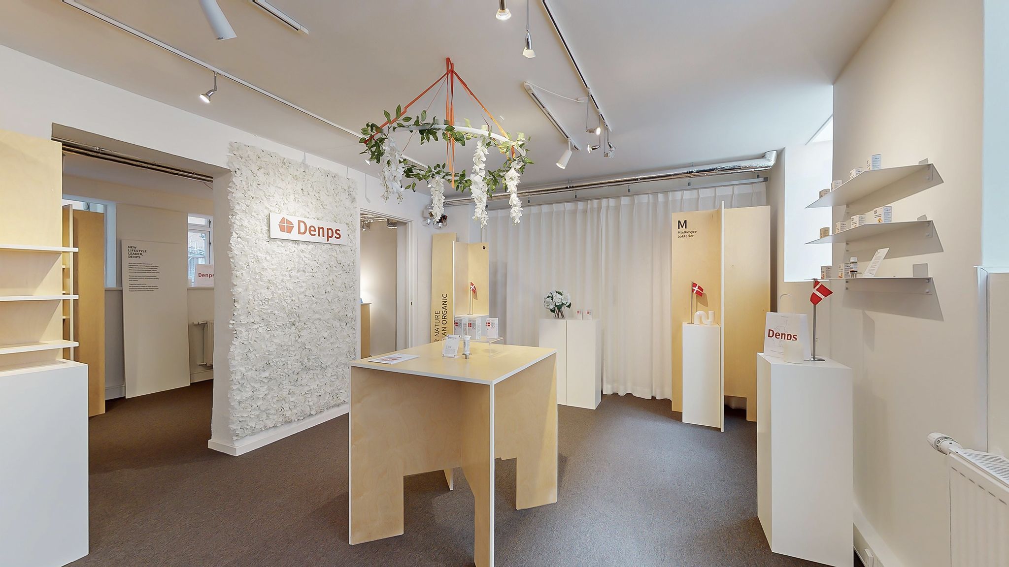 Det er det indre af den danske butik Denps med en hvid væg og en hvid væg med et Denps logo