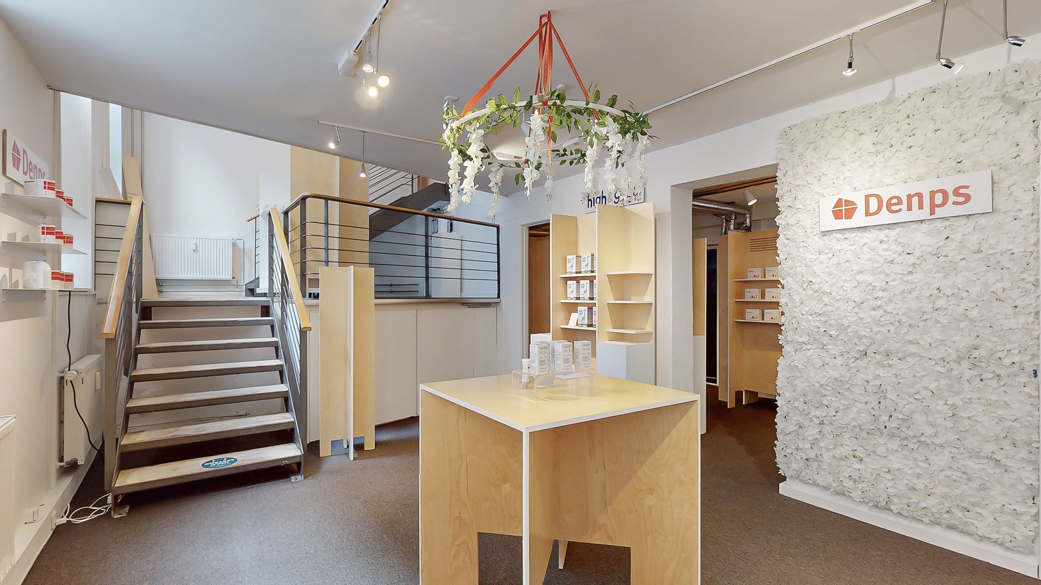 Moderne interiør med møbler, trappe og lysekroner, lysegul væg med tekst og logo Denps