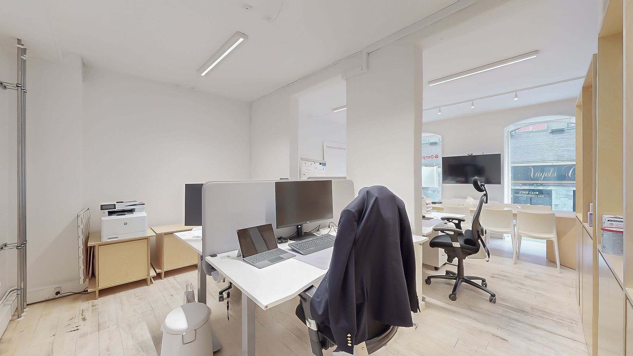 Moderne og ren kontor med højt til loftet og lyse loftslys, hvidt skrivebord, moderne skrivebordstelefon, to skærme, en