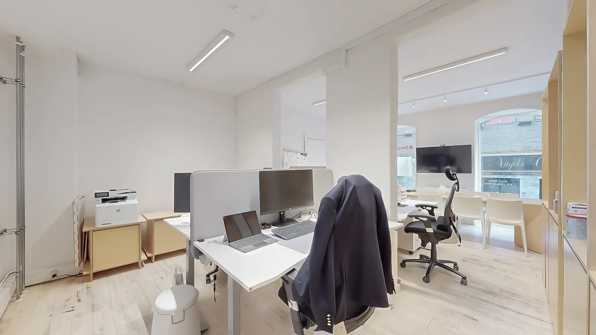 Moderne og ren kontor med højt til loftet og lyse loftslys, hvidt skrivebord, moderne skrivebordstelefon, to skærme, en