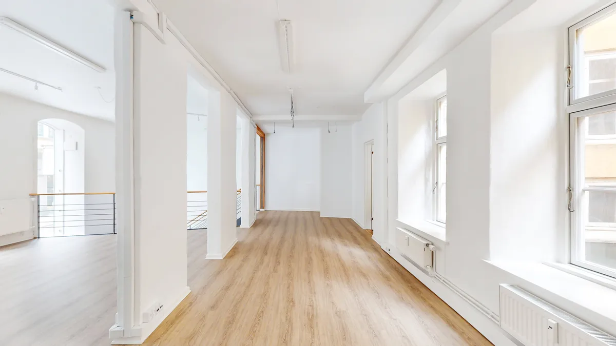 Foto af et lyst og pænt gulv med træbelægning i et nyt bygget lokale i København K. Lejligheden har højloft og store vinduer med udgang til en terrasse