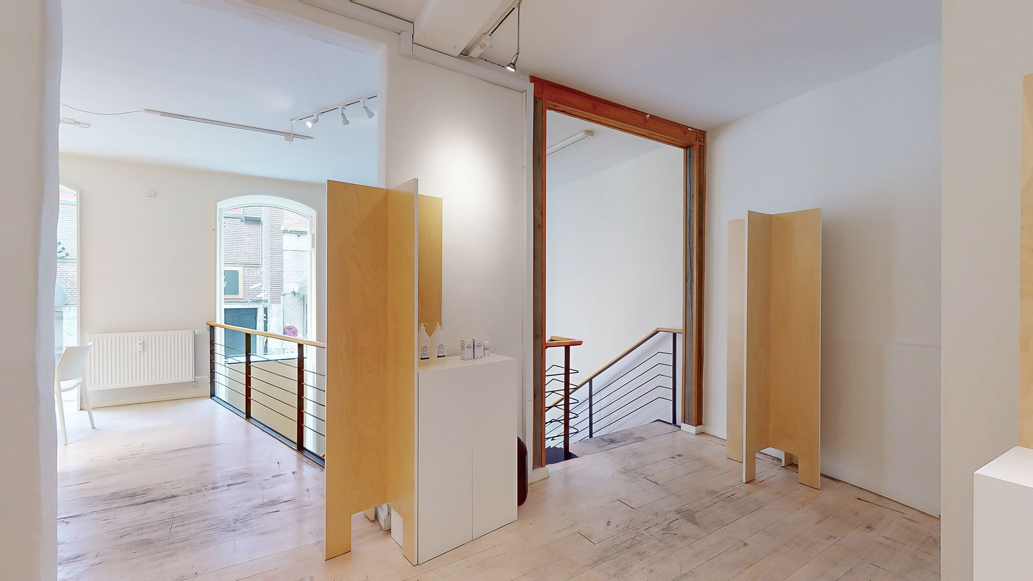 Et stort hvidt værelse med to høje, lyse skuffer og to høje, gule vægge. En hvid stol står ved en radiator. Værelset har