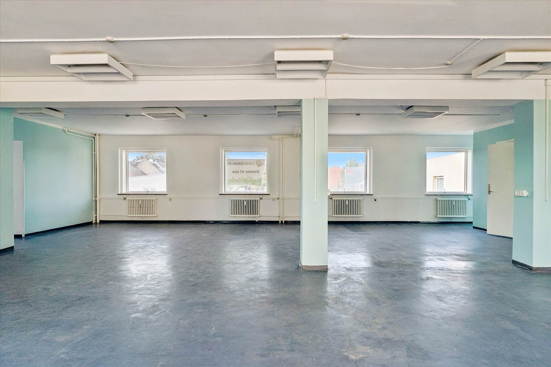 Et glasdækket kontorlokale med tre vinduer og en dør, hvor hver væg er malet i en blå og hvid farve.