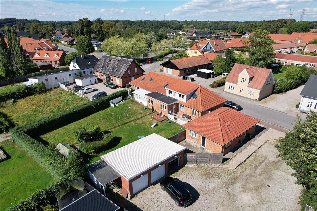 Byer med mange huse og garager, parkerede biler, grønne græsplæner og træer