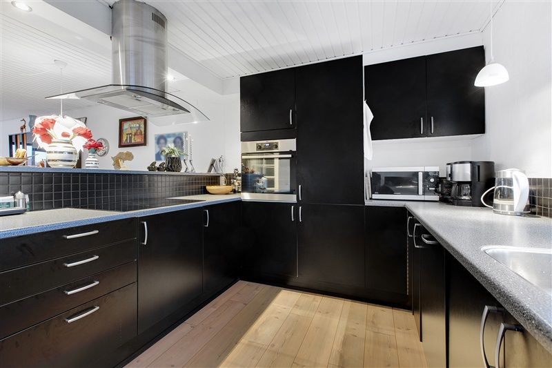 En moderne køkken med sort køkkenskabe og granit bordplade med elektriske apparater og dekorationer