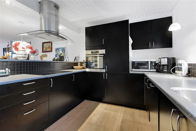 En moderne køkken med sort køkkenskabe og granit bordplade med elektriske apparater og dekorationer