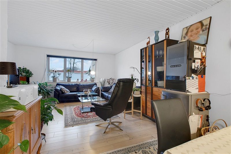 Et moderne interiør med en spisestue og sofa. Møbler og dekorationer inkluderer en tv-enhed, et skrivebord, og en sofa med