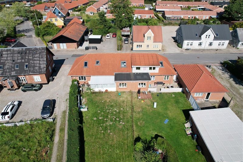 Flyfoto af en række hus med en stor parkeringsplads foran med flere biler parkeret