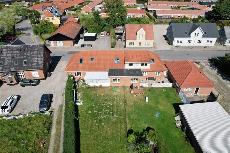 Flyfoto af en række hus med en stor parkeringsplads foran med flere biler parkeret